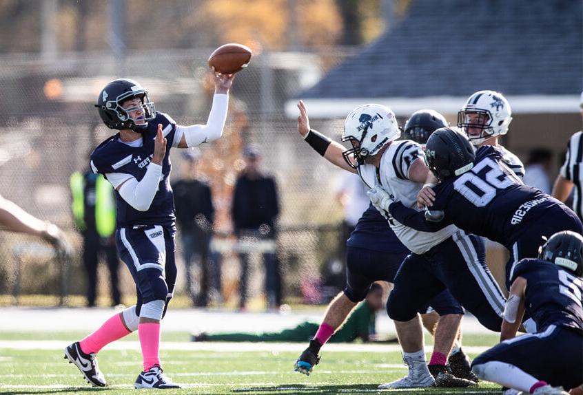 Poly Prep Varsity Football Quarterback throwing the ball as defense holds off the other team